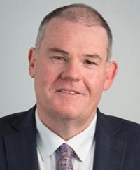 Matt Cahill. He is smiling wearing a white shirt, dark sports coat and tie.