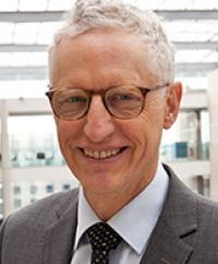 Dr David Gruen. He is smiling wearing glasses and a grey suit.