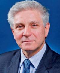 Chris Moraitis PSM. He is smiling wearing a dark blue suit.