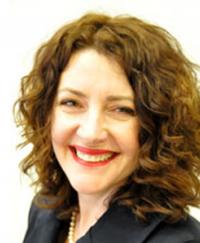 Clare Walsh. She is smiling wearing a black blazer.