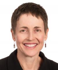 Portrait of Cath Patterson. She is smiling wearing a dark coat.