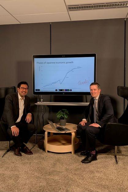 Dr Shiro Armstrong and Dr Paul Hubbard sitting in front of a screen with a graph displaying the Phases of Japanese growth.