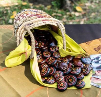 Basket of colourful painted Jawun Burnie Beans spilled onto a table next to a few scattered cards 