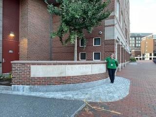 Photo of Tania Rishniw standing alongside sandstone entrance way outside Harvard school