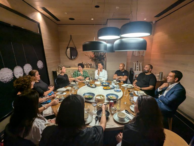 Photo of 11 people around a dinner table talking to each other 