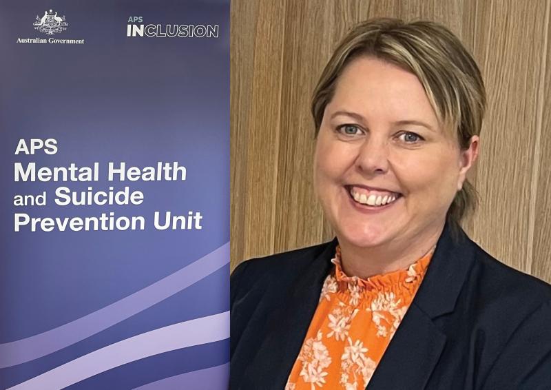 Rachael McMahon in front of a banner for the APS Mental Health and Suicide Prevention Unit