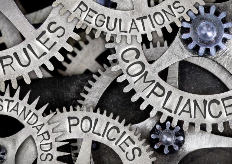 Interlocking cogs with the words rules, regulations, standards, compliance and policies written on the cogs.