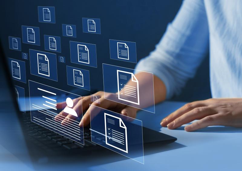 Illustrative image of person’s hands at laptop with overlay of document icons hovering in mid air in front of the person.