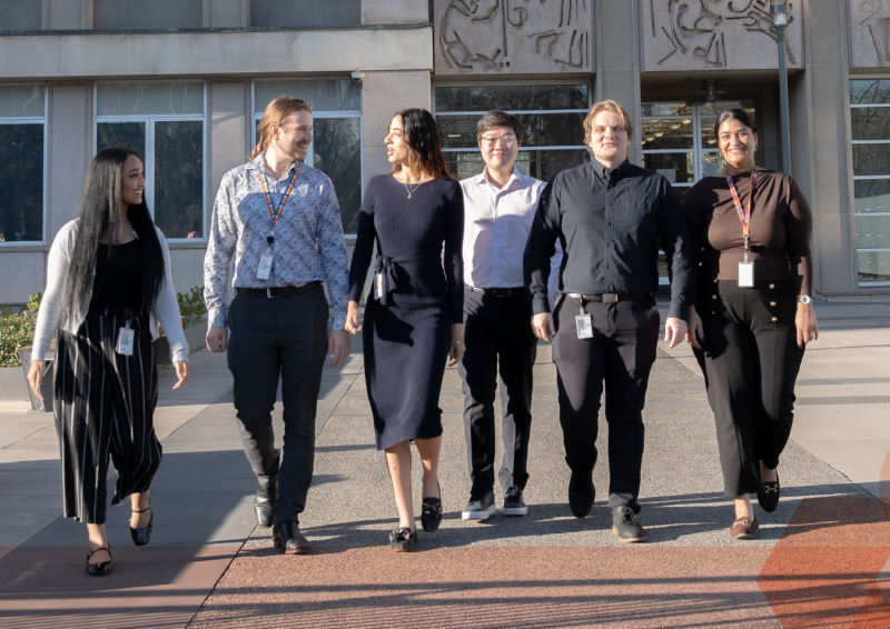 Team of six people walking out of office building