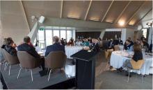 Members of the national regulators community of practice sitting at 4 dining tables listening to a panel discussion.