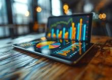 Illustrative image of ipad with bar charts and pie chart on it sitting on a desk