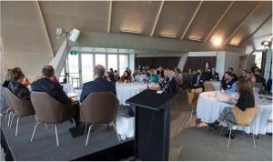 Members of the national regulators community of practice sitting at 4 dining tables listening to a panel discussion.