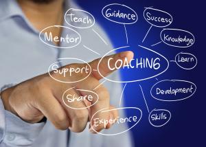 An illustration of a person with a finger pressing a screen with wording in circles that describe Coaching benefits.