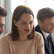 Two women and two men looking at two computer screens in a work environment.