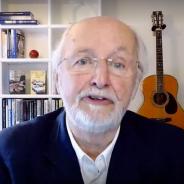 Image of Charles Jennings in his home office with bookshelf behind him and a guitar propped against wall. 
