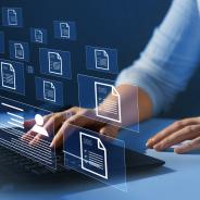 Illustrative image of person’s hands at laptop with overlay of document icons hovering in mid air in front of the person.