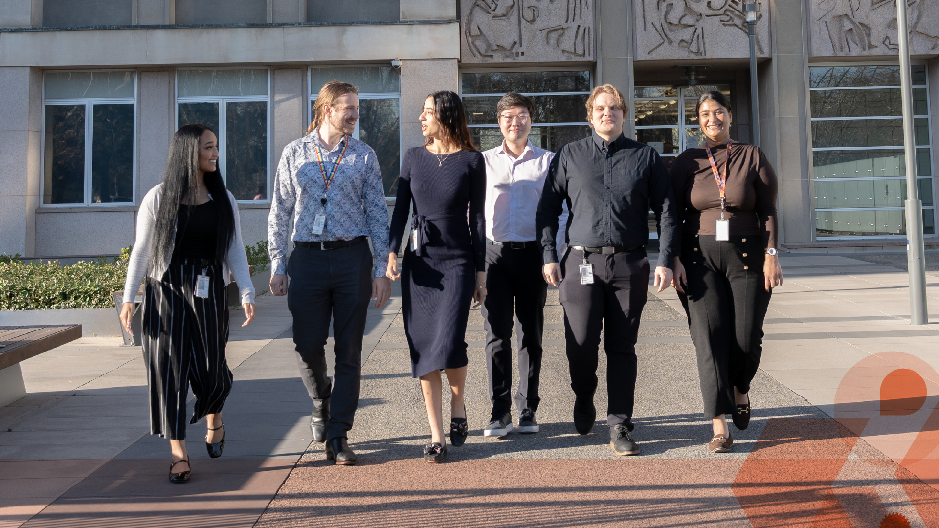 Team of six people walking out of office building