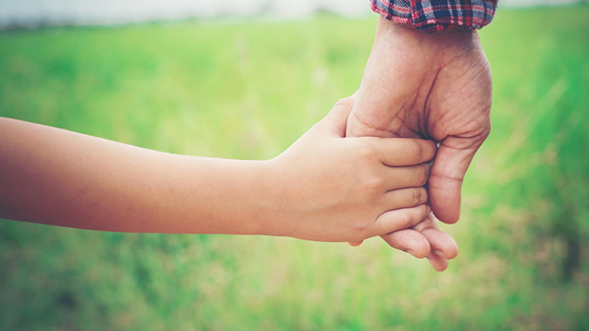 Adult hand holding a child's hand