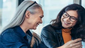 Two people smiling during conversation in professional environment