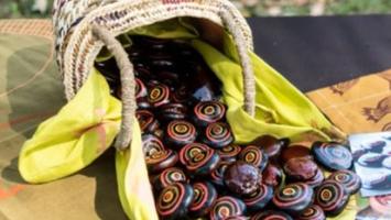 Basket of colourful painted Jawun Burnie Beans spilled onto a table next to a few scattered cards 