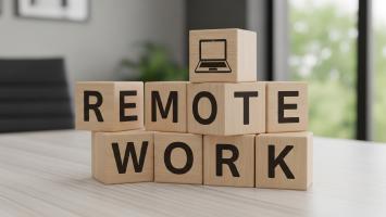An image of wooden blocks spelling remote work with laptop on home office desk.